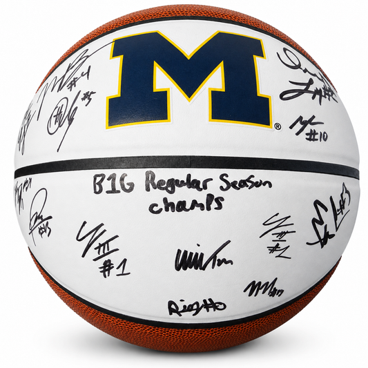 A Michigan basketball signed by multiple players, featuring the navy and maize 'M' logo on a white surface with black signatures and 'BIG Regular Season champs' written in the center.